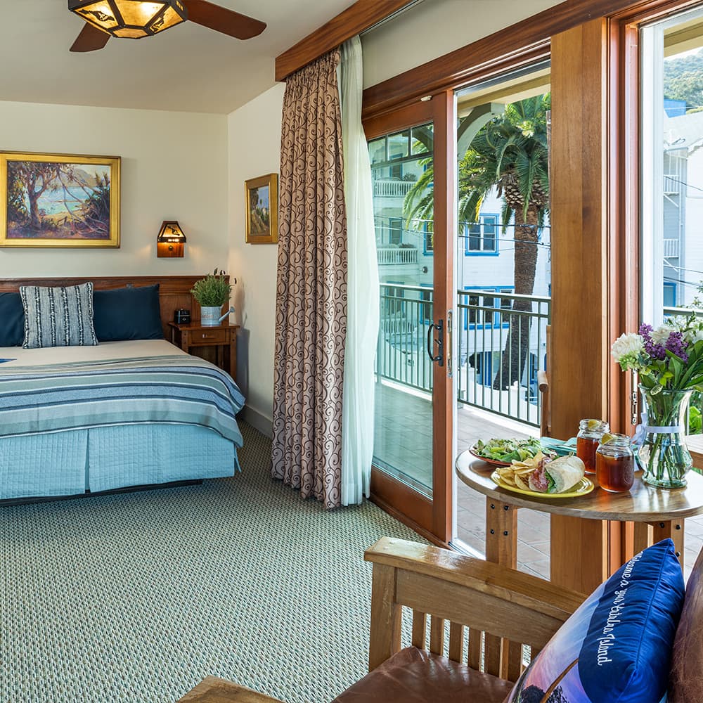 A cozy bedroom with a balcony, featuring modern decor and a small dining setup.