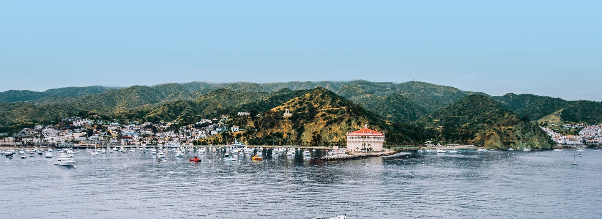 A panoramic view of a coastal town with boats and hills in the background.