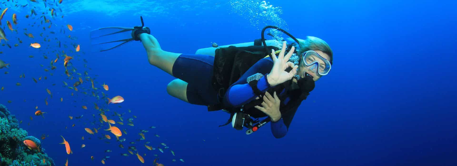 A female scuba diver is giving the “ok” signal