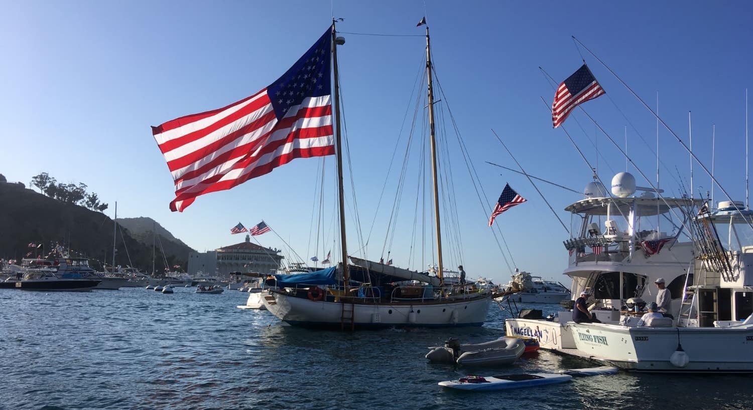 Multiple boats on the water with United States flags blowing in the wind