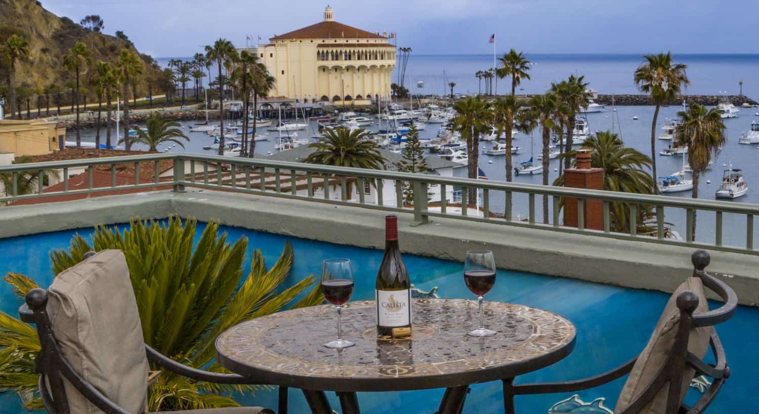 Property's rooftop with a patio table and chairs overlooking a harbor full of boats with the ocean in the background