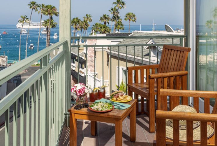 Balcony with wooden patio furniture and view of the ocean and harbor